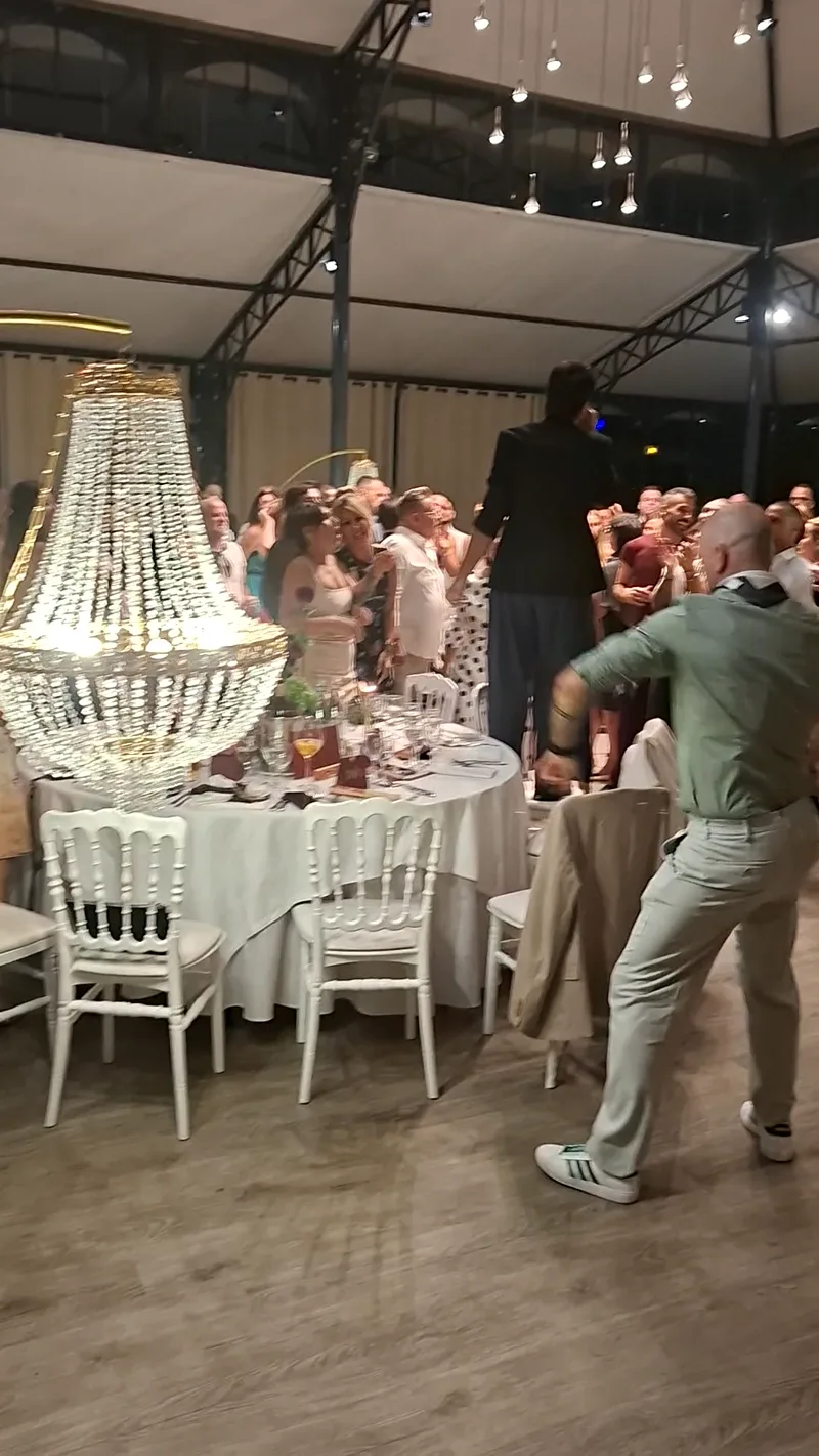 Lustre en cristal au premier plan et invités qui dansent lors d'un mariage dans un domaine