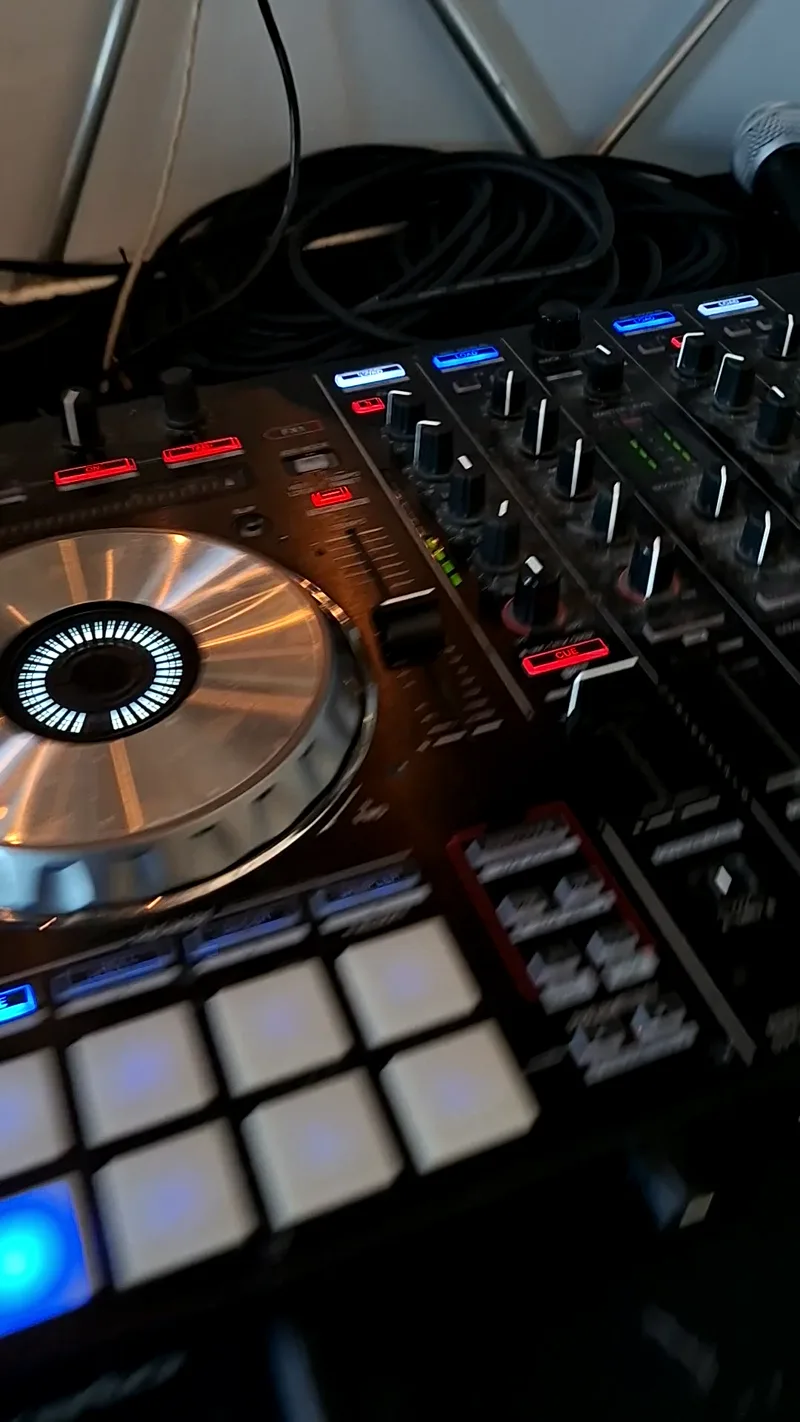 Platine de DJ éclairée en bleu pendant une soirée dansante