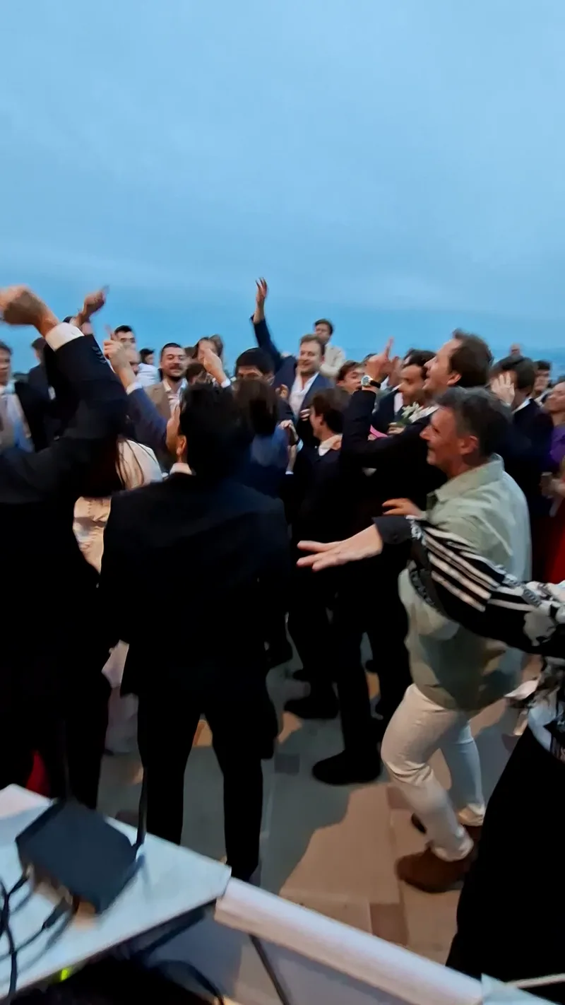 Invités en costume dansant en cercle au crépuscule lors d'une soirée de mariage sur la Côte d'Azur